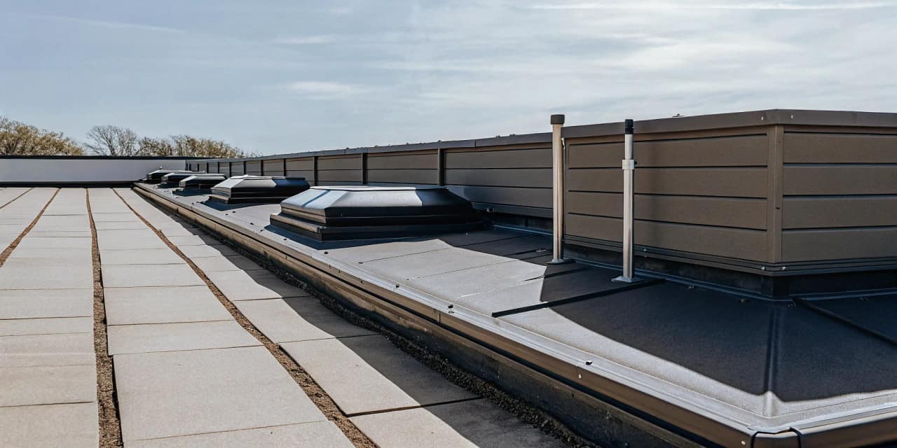 A clean modern commercial flat roof with functioning drainage outlets under a bright Texas sky